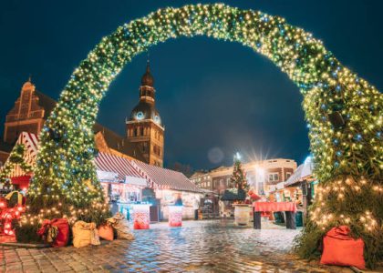 Riga, Latvia. Xmas Market On Dome Square With Riga Dome Cathedral. Christmas Tree And Trading Houses. Famous Landmark At Winter Evening Night In Illuminations Light.